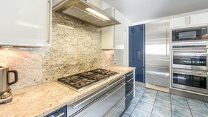 Una cocina moderna con electrodomésticos de acero inoxidable, encimeras de granito y piso de baldosas azules.
