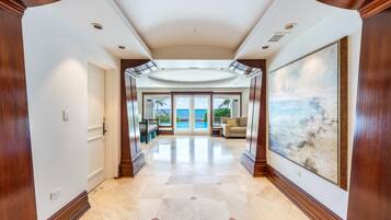 A spacious hallway with a view of the ocean, leading to a seating area with a large painting.