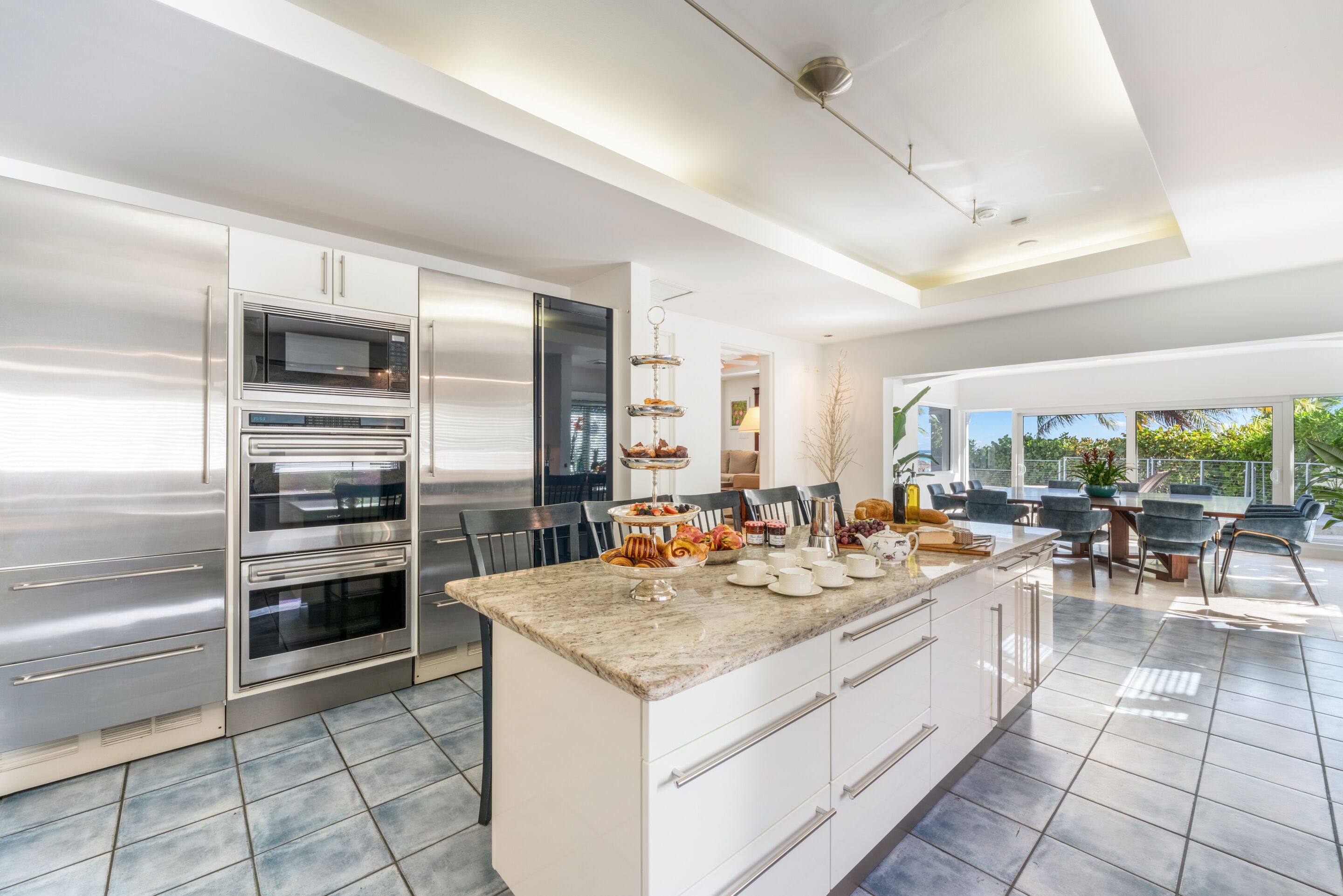 Una cocina moderna con hornos integrados, encimera de mármol y comedor con vistas.