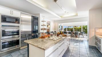 A modern kitchen with stainless steel appliances, a marble countertop, and a view to the outdoors.