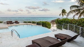 Zona junto a la piscina con sillones de descanso, una piscina pequeña y vista al océano.