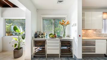 A modern kitchen with white cabinets, a built-in oven, and a window with blinds.