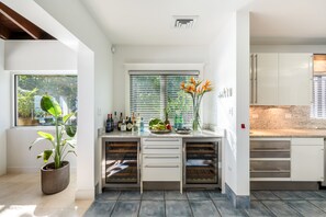Una cocina moderna con armarios blancos, horno empotrado y ventana con persianas.