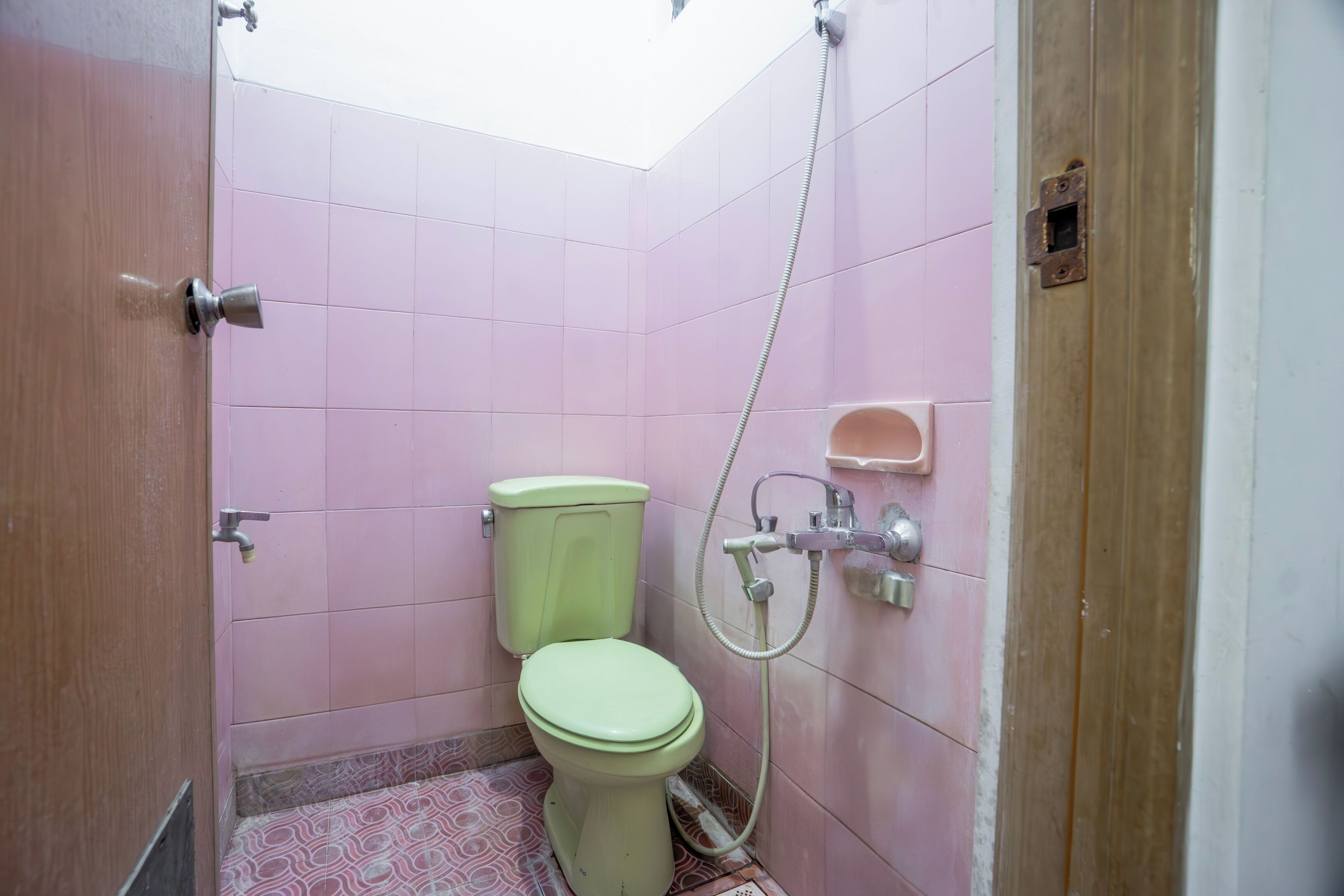 A small bathroom with a toilet, shower, and pink tiled walls.