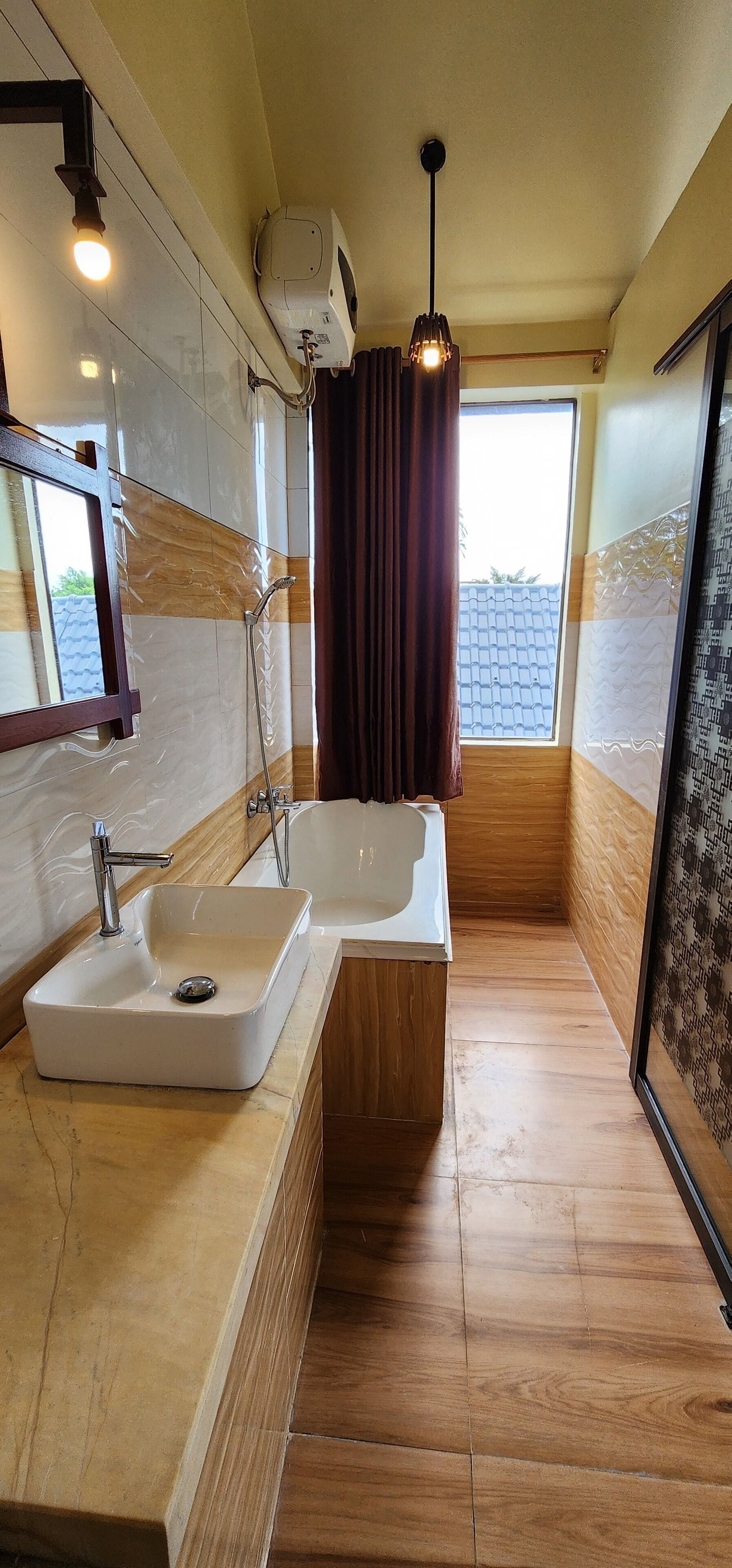 A modern bathroom with a large sink, a bathtub, and a shower. There is a window with curtains and a ceiling-mounted air purifier.