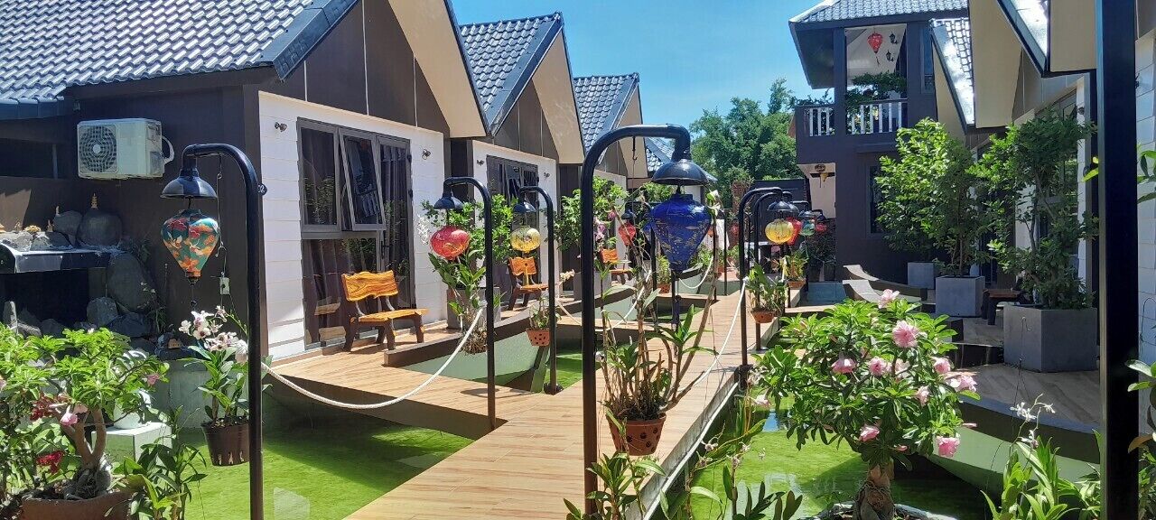 Un patio con plantas en macetas, asientos al aire libre y una terraza de madera.