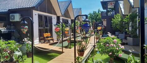 Un patio con plantas en macetas, asientos al aire libre y una terraza de madera.