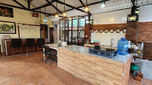 A kitchen with a central island, a stove, and a large water dispenser. - Hoi An Coco Bungalows (Da Nang)