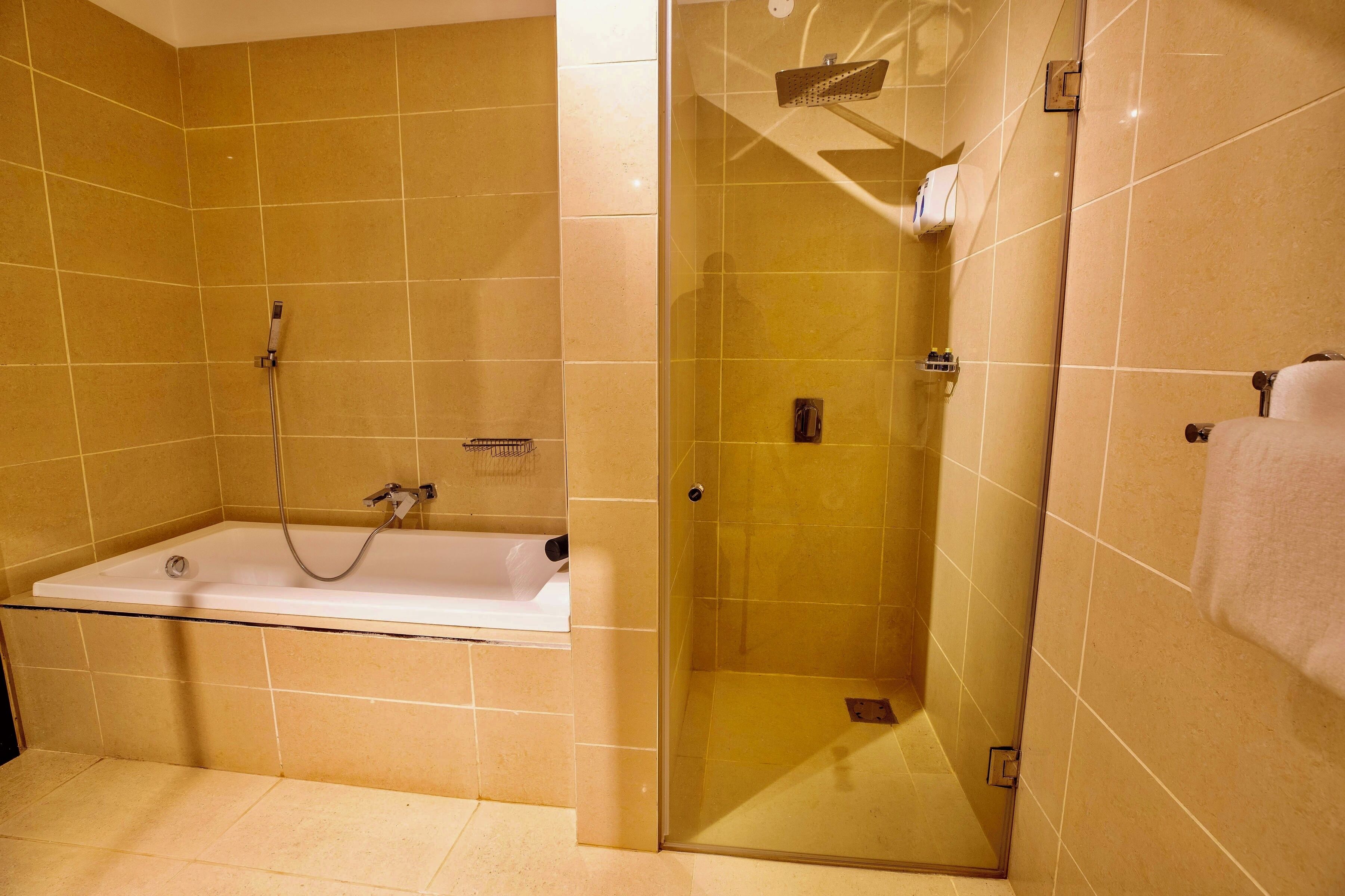 Un bagno con una vasca, una cabina doccia in vetro e un porta asciugamani.