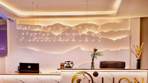 A hotel reception desk with a marble counter, a laptop, a clock, and a decorative plant. - Lion Villas (Nairobi)