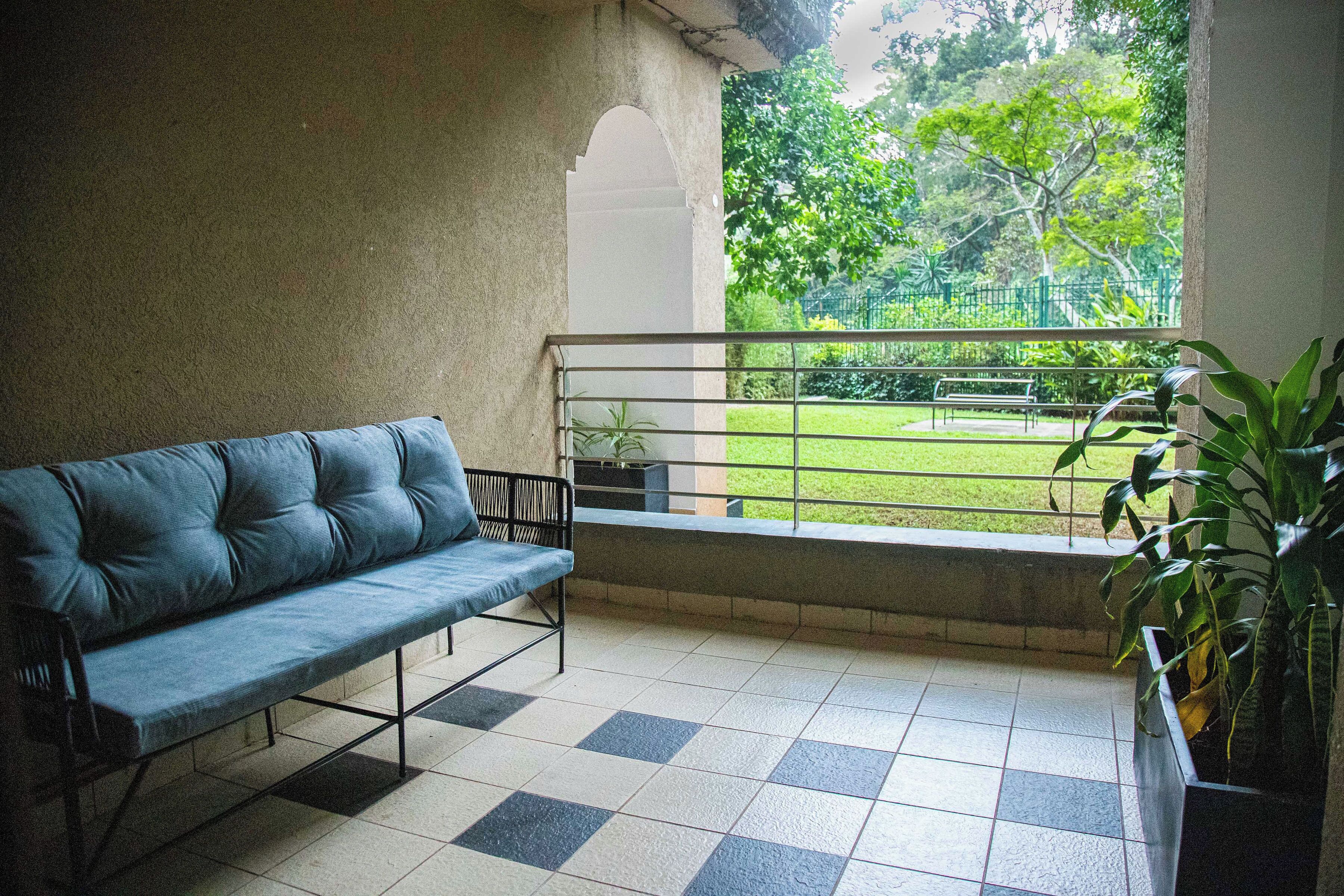 A balcony with a checkered floor, a blue sofa, and a railing.