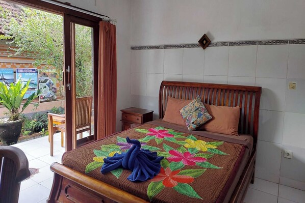 Un dormitorio con cama de madera, una mesita de noche pequeña, una ventana con cortinas y vistas al exterior con vegetación.