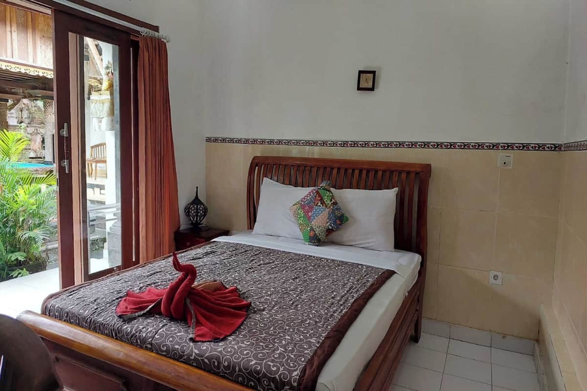 Une chambre d’hôtel avec un lit, une table de chevet, une fenêtre avec des rideaux et une vue sur la verdure.