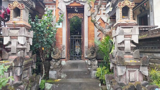 A temple entrance with ornate stone carvings, a central doorway, and steps leading up to it. - Super OYO Capital O  Pondok Ayu Homestay (Ubud)