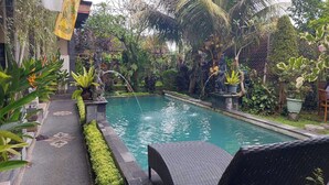 A pool surrounded by lush greenery and a flag. - Super OYO Capital O  Pondok Ayu Homestay (Ubud)