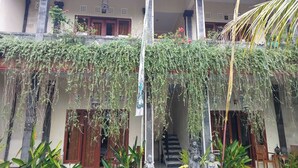A traditional building with a covered porch, stone columns, and hanging plants. - Super OYO Capital O  Pondok Ayu Homestay (Ubud)