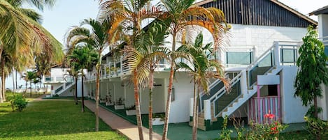 A resort with a white building, palm trees, and a staircase leading to the entrance.