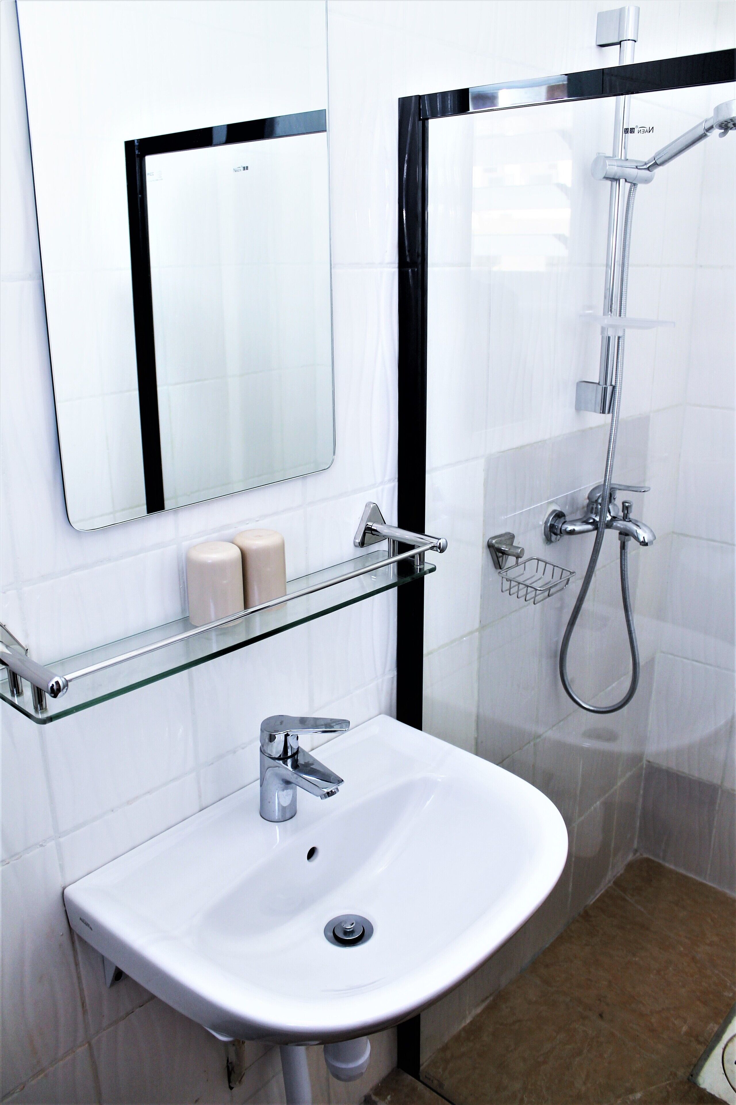 Une salle de bain avec un lavabo blanc, un miroir et une douche.