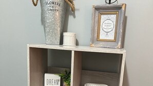 A wooden shelf with a sign that reads "Dream," a small potted plant, a woven basket, and three black geometric objects. - NEW - Minimalistic Farmhouse! (Jacksonville)