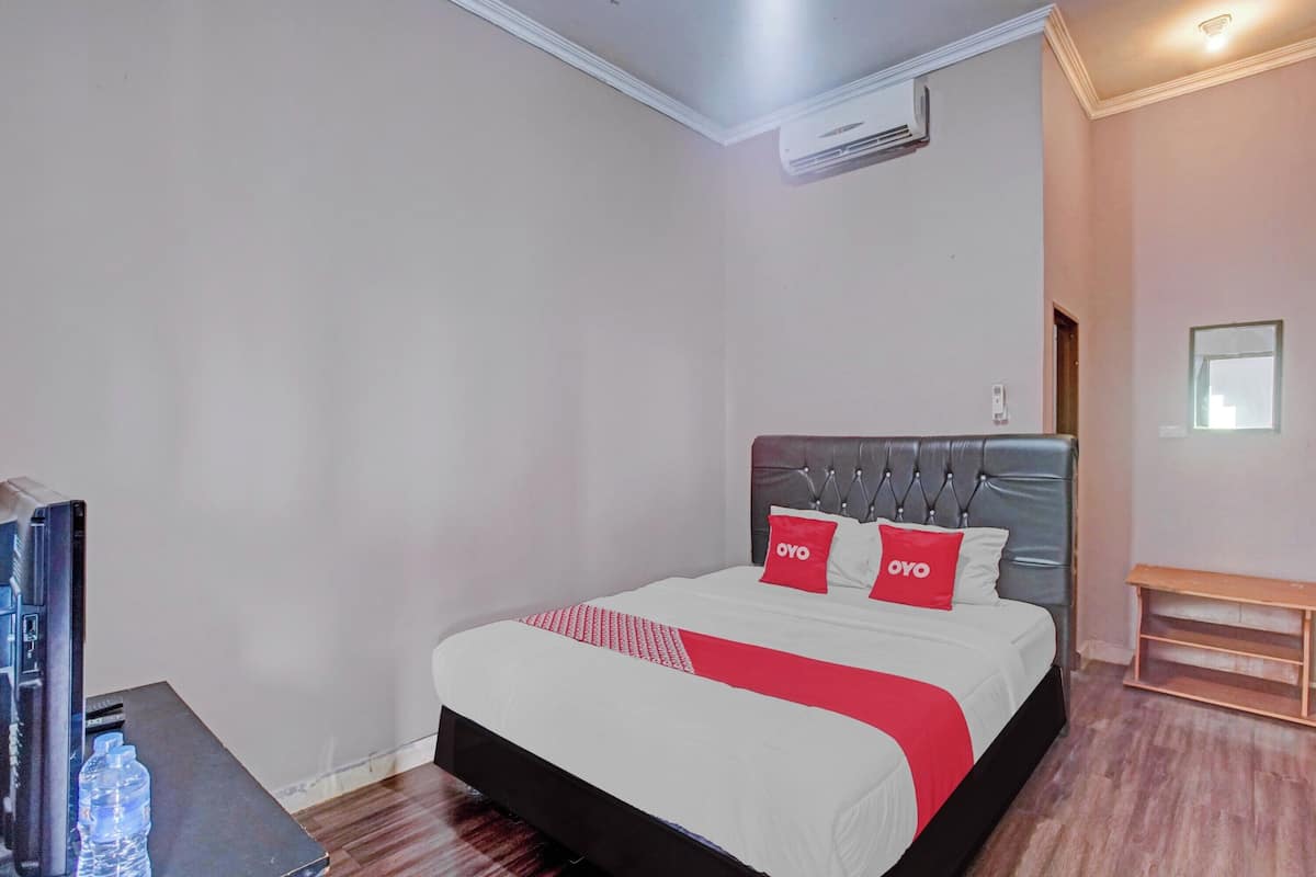 A neatly arranged hotel room with a bed, a TV, and a water bottle on a table.