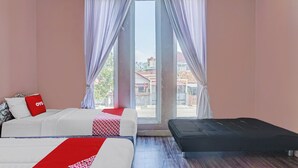 Une chambre d’hôtel avec un lit, un banc et une grande fenêtre avec des rideaux.