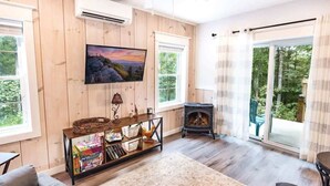 Ein gemütliches Wohnzimmer mit Holzwänden, einem Kamin, einem Fernseher und einem großen Fenster.