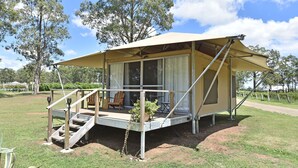 Une structure de camping dotée d’un porche couvert, d’un escalier et d’un espace détente avec des chaises.
