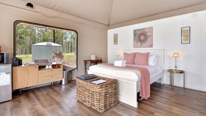 Ein Schlafzimmer mit Bett, Schreibtisch, Mülleimer und Blick ins Freie.