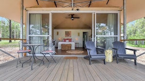 A covered outdoor area with a wooden deck, two tables, and four chairs.