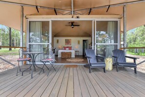 A covered outdoor area with a wooden deck, two tables, and four chairs.