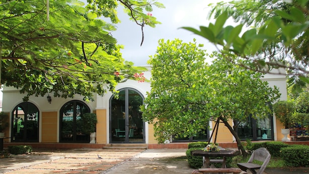 A courtyard with a stone pathway, a wooden table, and a chair. - Grand Smile Wellness Resort (Pattaya)