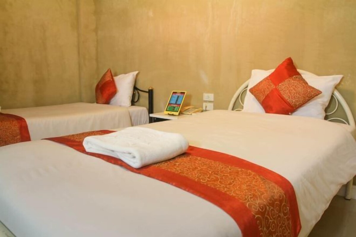 A hotel room with two beds, each with a red and white bedspread, and a white towel on the bed in the foreground.