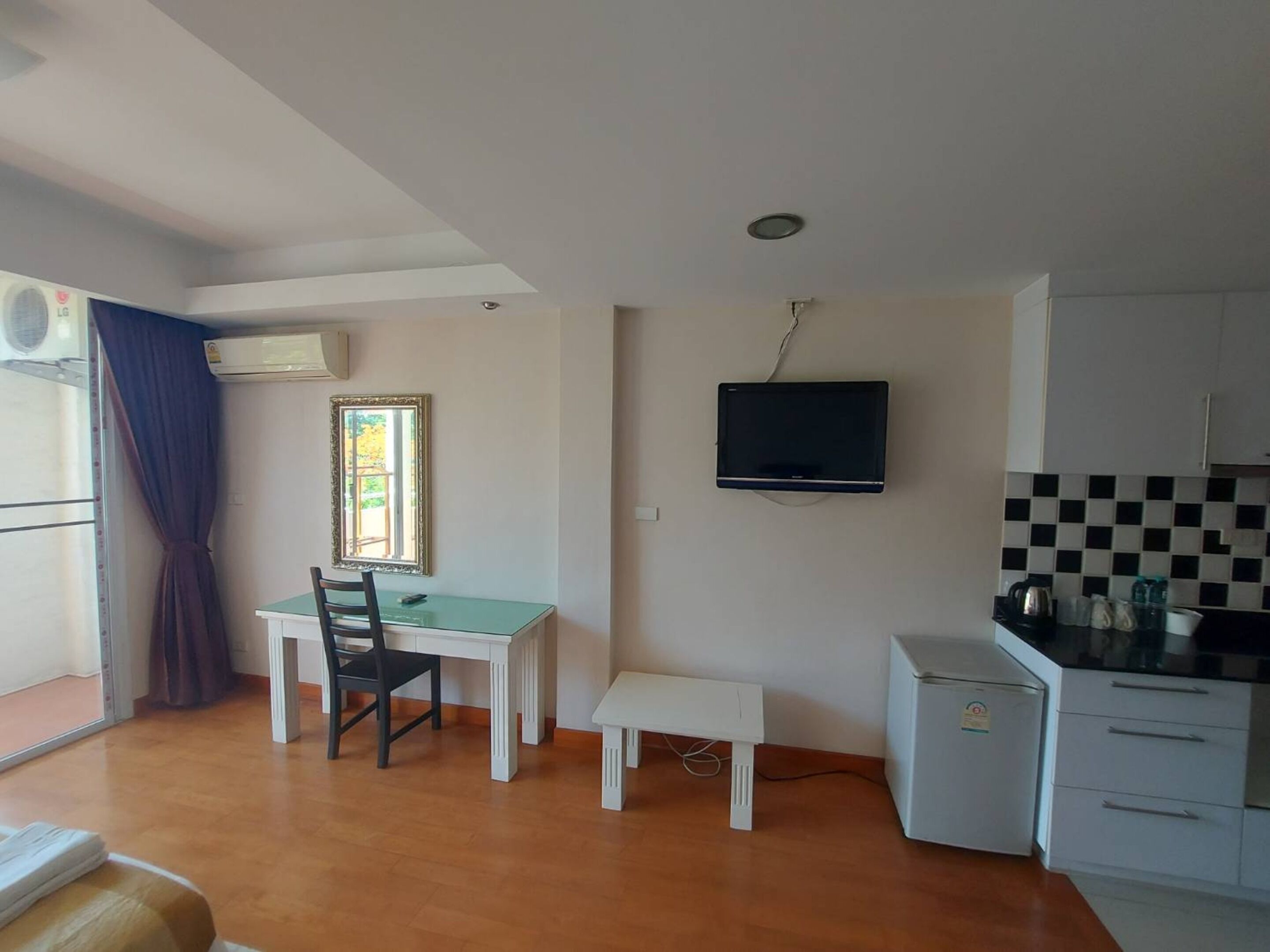 Um espaço de estar compacto com área de jantar, uma kitchenette pequena e uma televisão na parede.