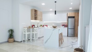 Een moderne keuken met witte kastjes, een marmeren eiland en een roestvrijstalen koelkast.