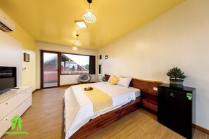 Een slaapkamer met een bed, een televisie, een koelkast en een raam met uitzicht.
