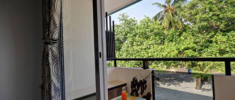 A balcony with a view of a beach and palm trees.