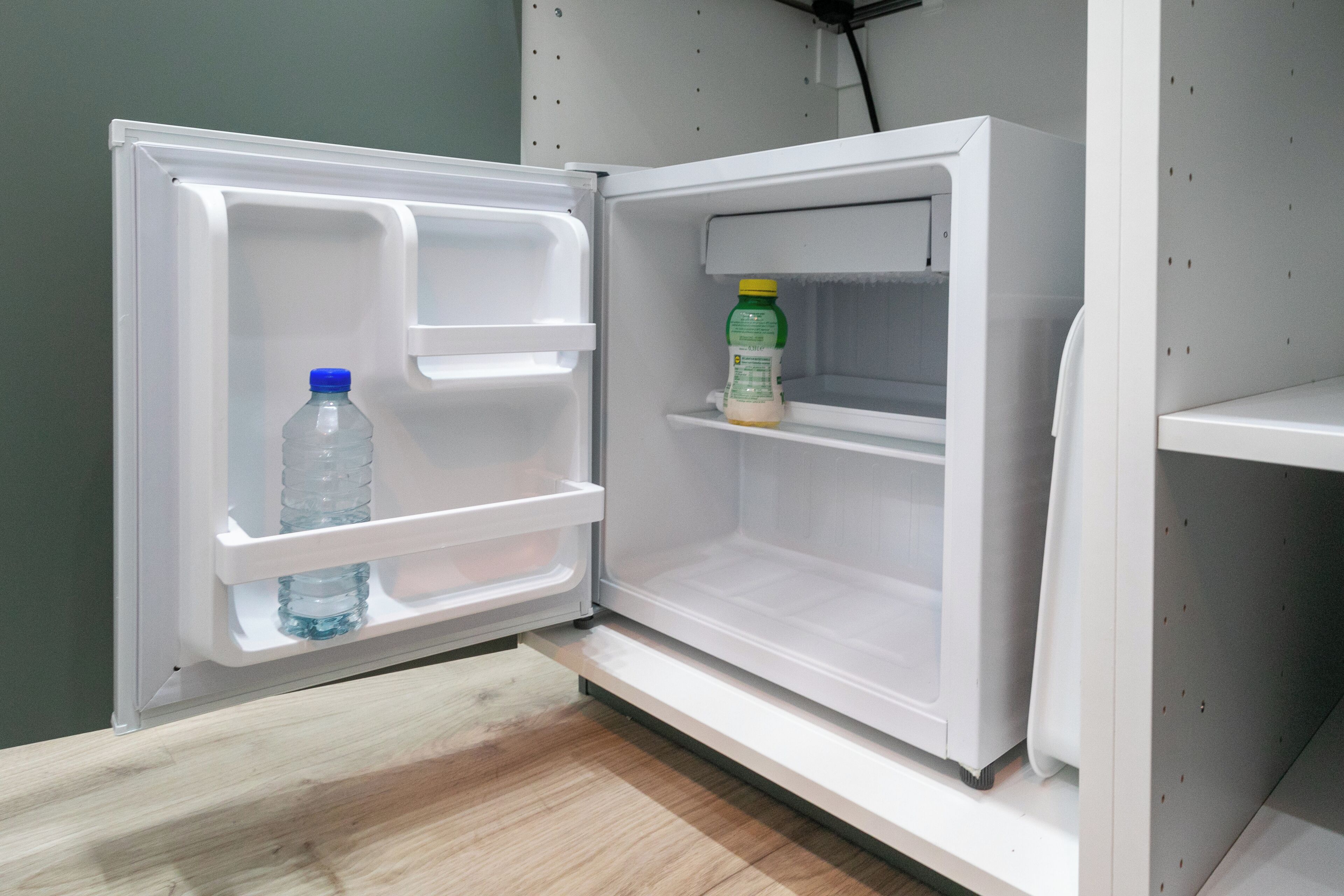 Ein offener Kühlschrank mit einer Flasche und einer Milchkarton auf den Regalen.