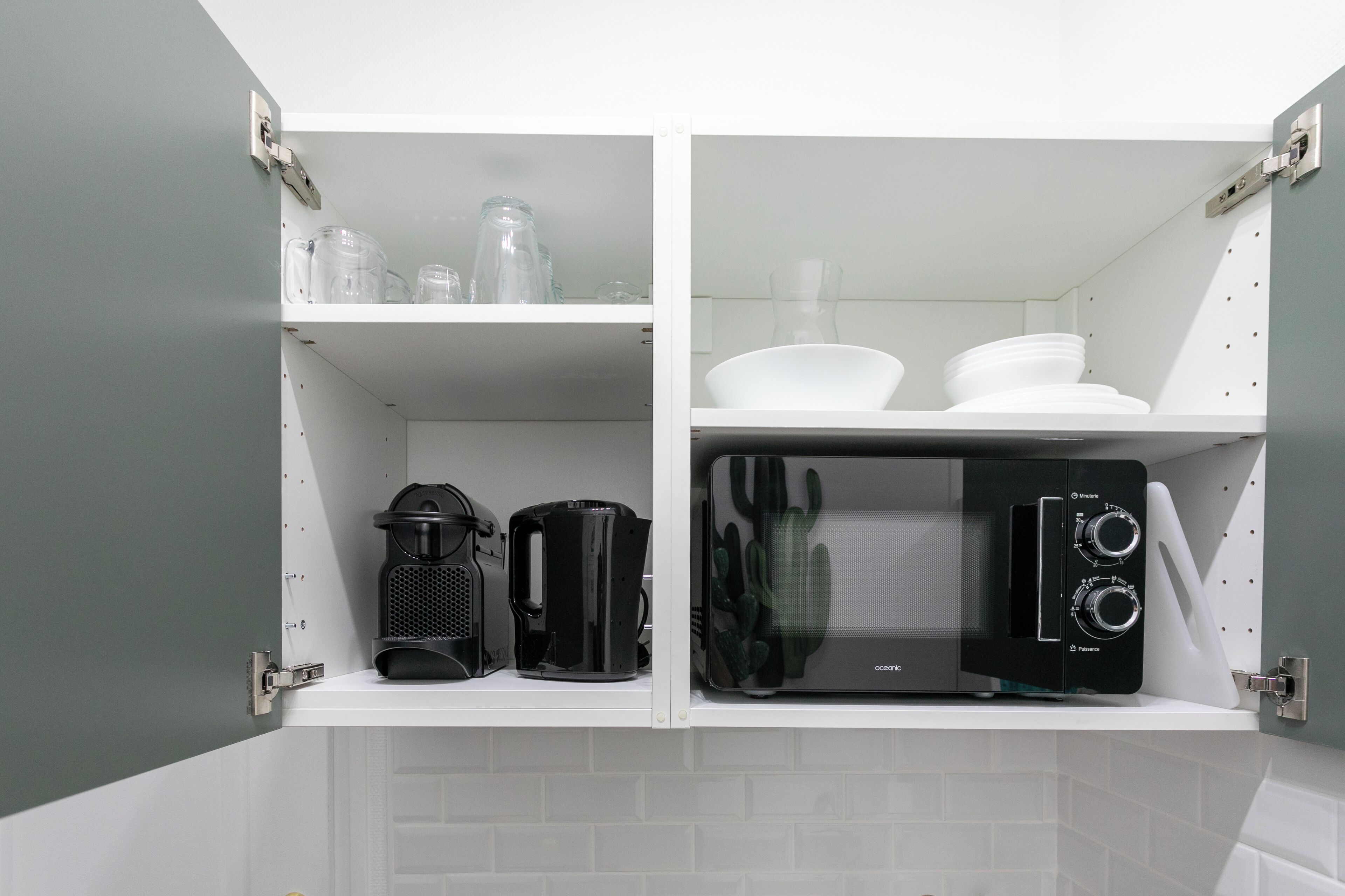 A kitchen with white cabinets, a coffee maker, a microwave, and a cactus on the counter.