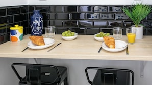 Un desayuno con croissants, uvas y zumo de naranja sobre una mesa de madera.