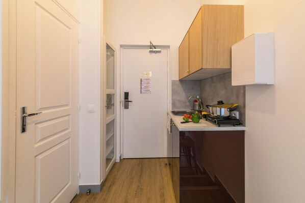 Une cuisine étroite avec des meubles de rangement en bois, un évier et une cuisinière.
