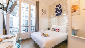 Een hotelkamer met een bed, een eettafel en een raam met uitzicht op gebouwen.