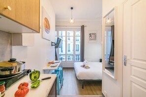 Une chambre d’hôtel compacte comprenant un coin cuisine, un espace repas et un lit.
