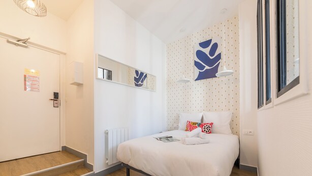 A modern hotel room with a bed, a radiator, a mirror, and a window. - WS Haussmann - La Fayette (Paris)