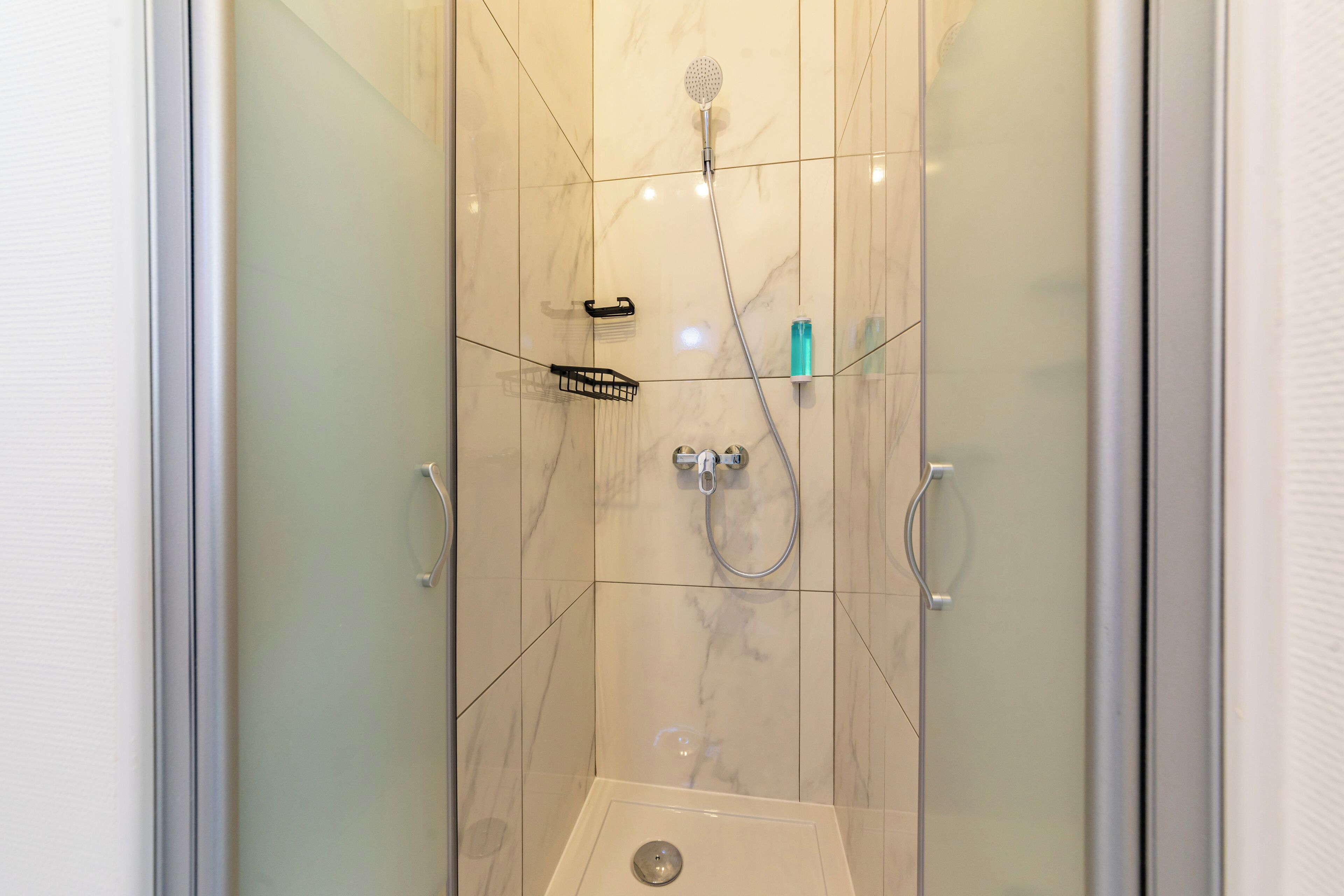 A modern shower with a handheld showerhead, a handheld showerhead, and a handheld showerhead.