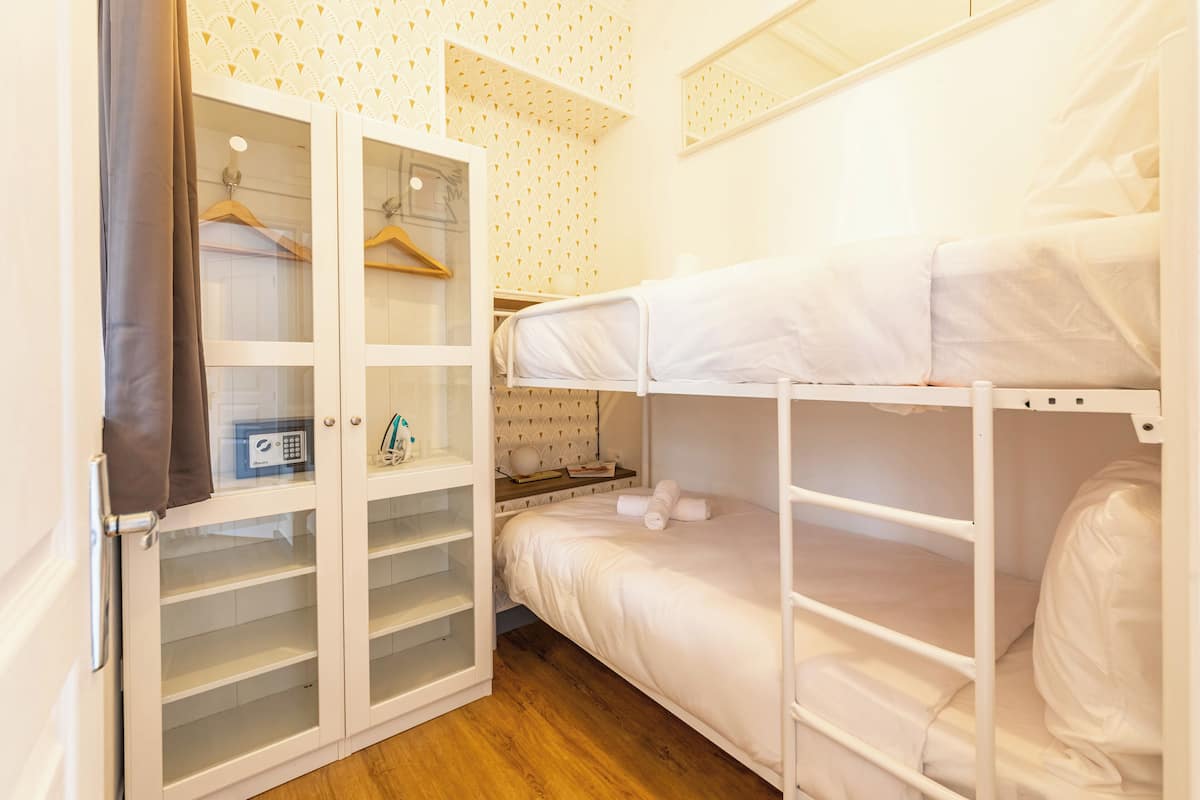 A bunk bed room with a wardrobe and a small table.