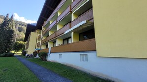 A multi-story hotel with balconies, a paved pathway, and a mountain backdrop. - TUDOR STUDIO (Kaprun)