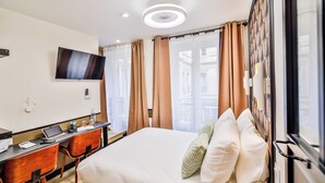 A hotel room with a bed, a desk with a laptop, a TV, and a window with curtains. - WS Louvre - Saint-Florentin (Paris)