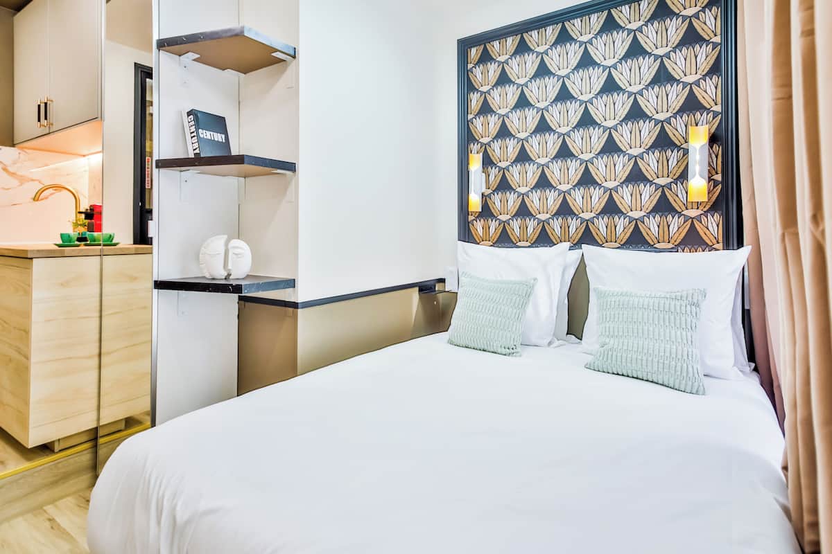 A hotel room with a bed, a nightstand, a mirror, a wardrobe, and a bathroom.