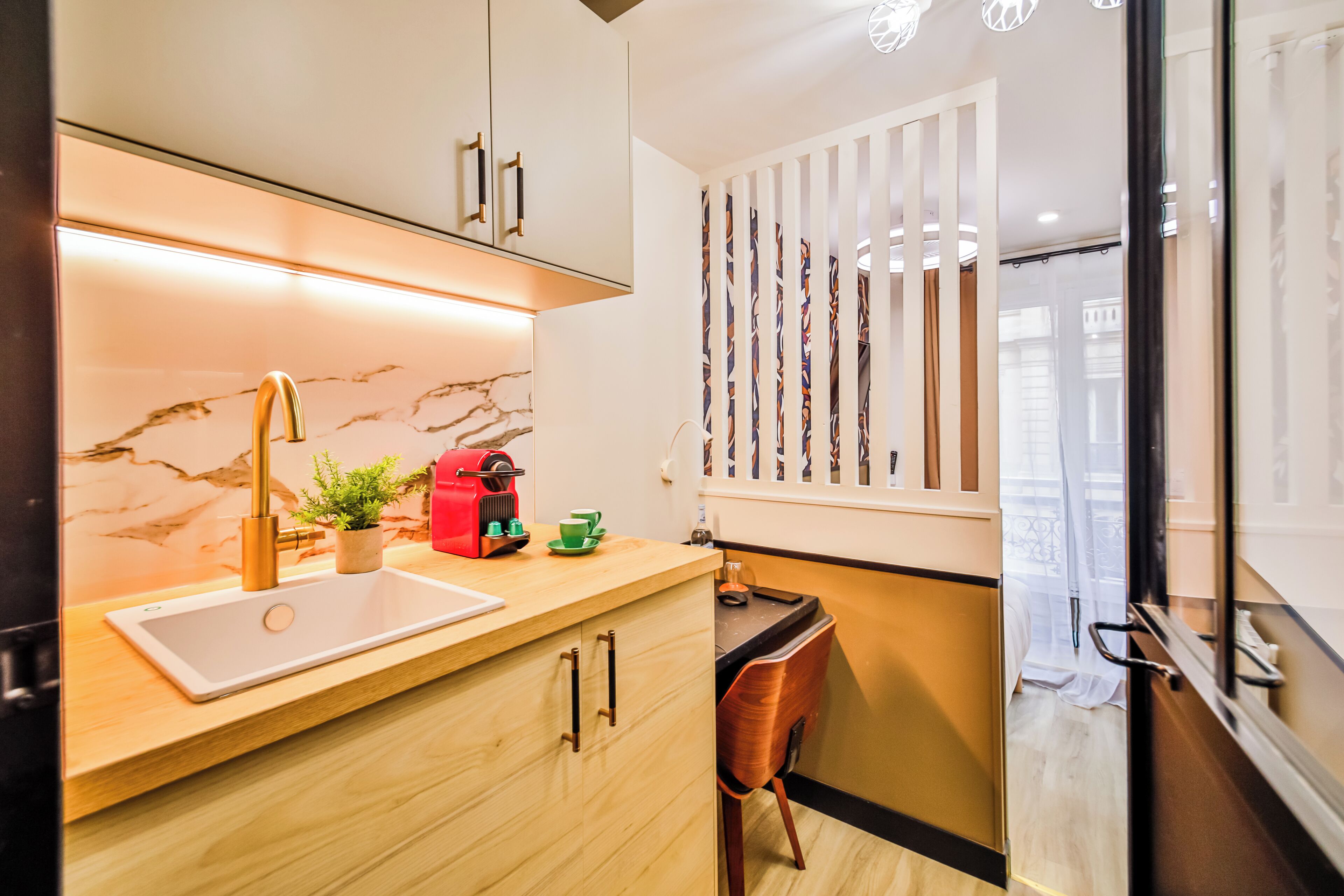 A modern kitchen with a marble backsplash, a sink, and a countertop with a coffee machine.