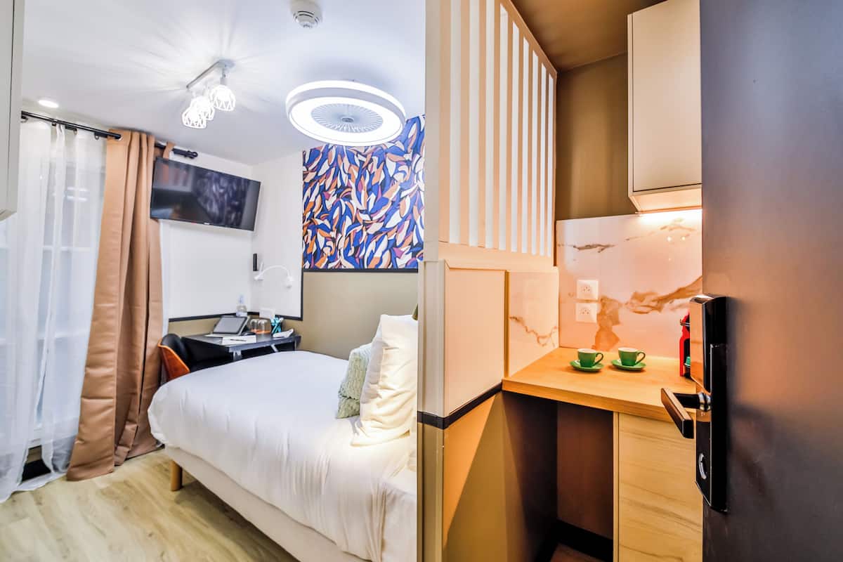 A hotel room with a bed, a desk, a TV, and a bathroom.
